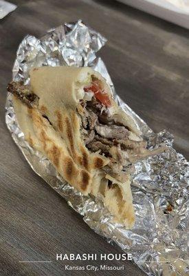 Half eaten beef shawarma, added garlic sauce.