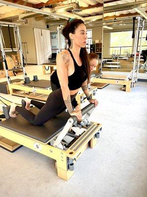 A client working out on the reformer while instructor Cherie cues her.