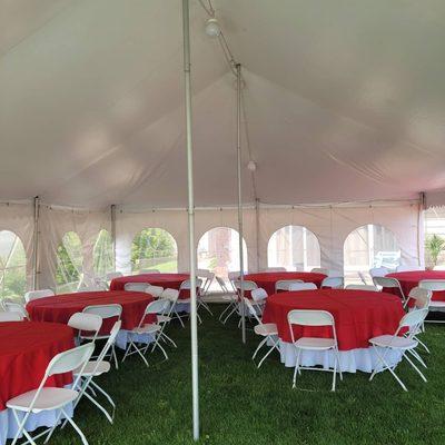 20x30 rope and pole tent with 60" round tables, white folding chairs, white 120" linens with 90" red overlays.