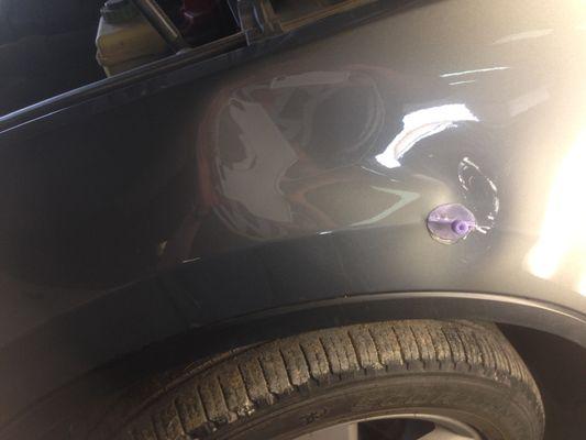 Glue tabs being used to remove a big dent on this vehicles left fender.