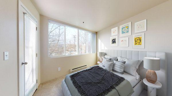 Bedroom with carpeted floors, a large window, and closet space.