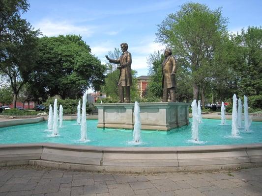 Lincoln and Douglas debating with the Reddick Mansion seen through the trees in the background.