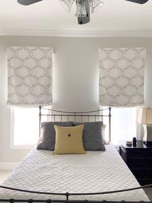 Hobbled roman shades as the window treatments in this bedroom add charm to the restful bedroom decor.