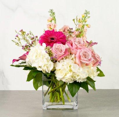 Bridgette - This sweet arrangement is perfect for a side table or coffee table. It's filled with roses, gerberas hydrangea & stock in vase.