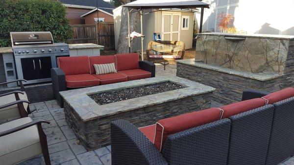 Outdoor fire pit, water feature and kitchen in natural stone