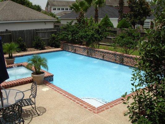 New construction pool with brick ledge retaining wall and brick pool spa. Learn more: https://pulliampoolshouston.com/swimmin...