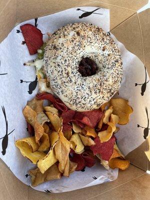 Chicken sandwich with avocado, mozzarella, sundries tomatoes and vegetable root chips on an everything bagel