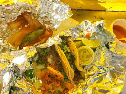 Two barbacoa and one deshebrada tacos along with complementary sautéed onion, roasted jalapeño and a small portion of charros.