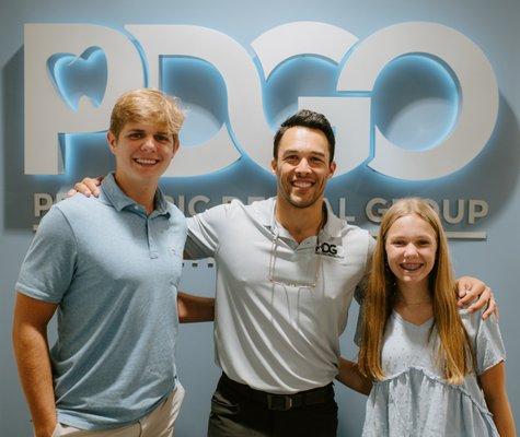 Dr. Collazo with 2 happy orthodontic patients with beautiful smiles.