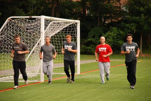 College baseball players warming up with Coach Steve prior to a sprint training session.