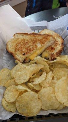 Triple cheese panini with a side of chips.