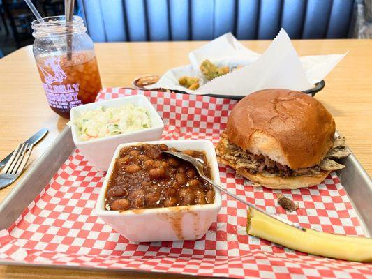 Pulled pork sandwich with beans, coleslaw, and fried okra