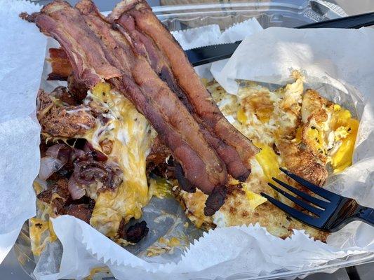 Crisp bacon, fried eggs, and fried potatoes with cherry tomatoes, cheese, and caramelized onions