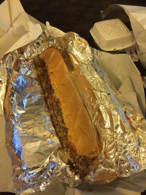 Philly cheesesteak with mushrooms. Mozzarella sticks are in the container behind it.