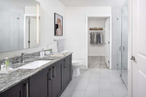 Luxury bath with walk-in closet and glass-enclosed shower at Camden Central high-rise apartments in St. Petersburg, FL