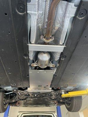 Before and after shots of catalytic converter shield installation.