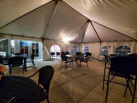 Outdoor patio has a huge heated tent with spaced apart tables and chairs