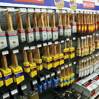 A well-organized display of high-quality Wooster and Purdy paint brushes in various sizes, showcased on a retail pegboard, pr...