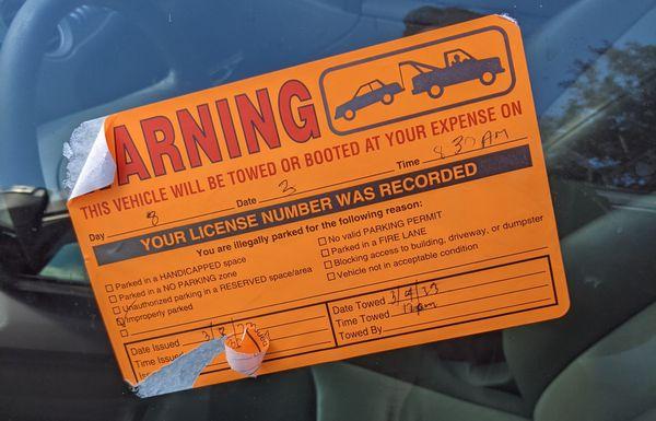 unofficial/non-policed parking ticket sticker left on my car by building owners inside the parking lot