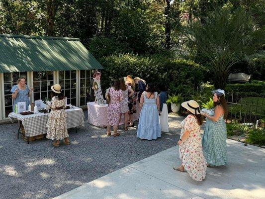 Tea party guests browsing vendors set up in the garden