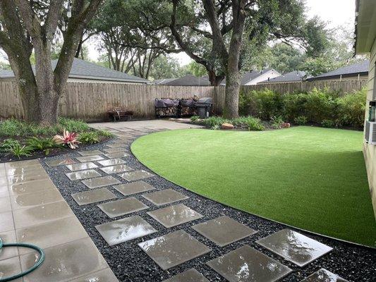 backyard landscape renovation with black-star gravel and paver patio with pet friendly artificial grass and installation of lawn sprinkler.