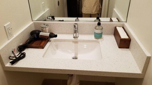 Men's locker room sink area.  Hair dryer, hand wash, and q-tips