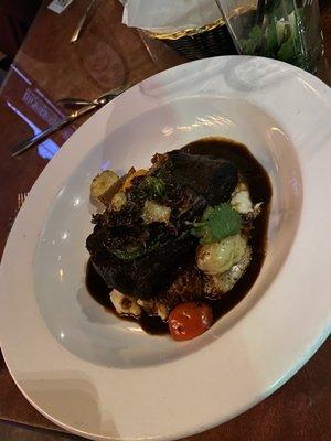 Beef Short rib braised for 8 hours, served over mashed potatoes with roasted Brussel sprouts, tomatoes, and small potatoes.