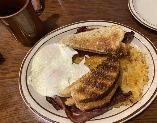 Over easy eggs, bacon, and hash browns with wheat toast