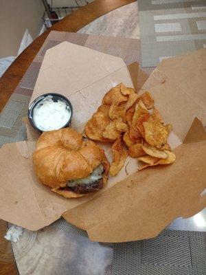 Fillet croissant with chips and dip in a takeout box