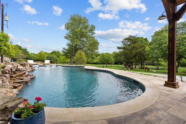 Dive into pure bliss in our freeform pool, where cascading water from a stacked boulder feature adds a touch of natural beauty.