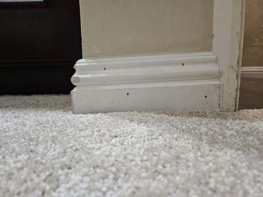 Crooked baseboard with exposed nail holes