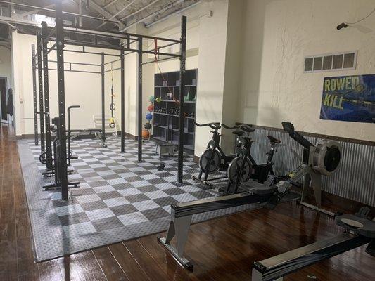 Functional training area with rowing machines, spin bikes, and an air assault bike.