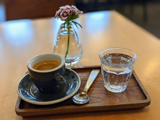 Birthday Blend double Ethiopian espresso shot, neat, presented charmingly with a little glass of sparkling water.