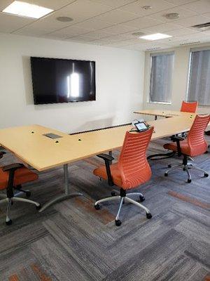 A small, modern meeting room featuring a unique, modular conference table with light wood surfaces and built-in connectivity ...