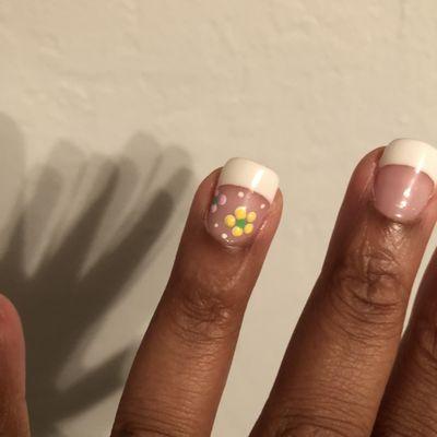 Natural nail Gel French tip with accent flowers on ring finger close up