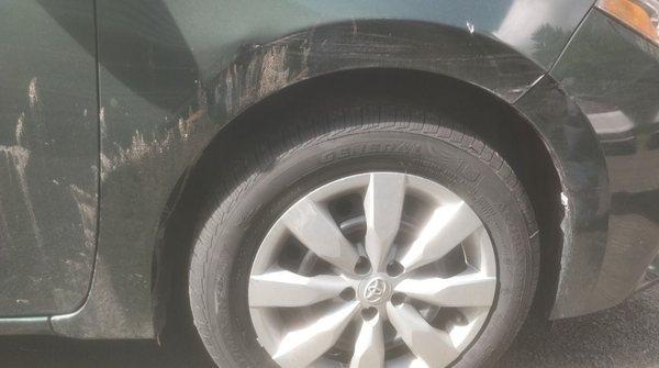 Large dent to the left of the wheel, large scratches above.