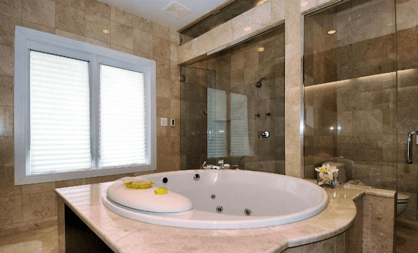 Luxurious bathroom in Crema Nouva marble with framless glass shower doors.