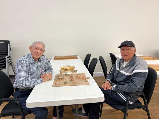 Elderly enjoying their afternoon over a light game of Chinese chess.