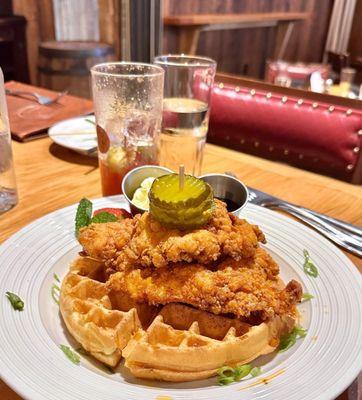 SWEET CHICKEN & WAFFLES - Fried chicken placed on a Belgian waffle, topped with candied pecans, maple syrup, powdered sugar, and strawberry.