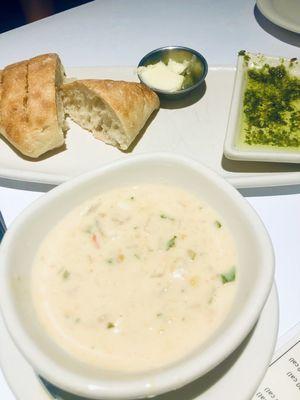 Complimentary warm bread with butter and pesto dipping oil. Corn chowder has potatoes and bacon.