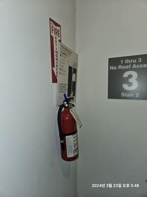 Evacuation safety sign nicely balanced on top of the fire extinguisher