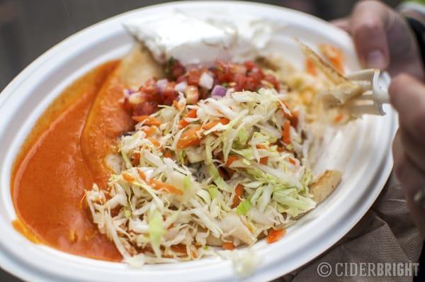 A delicious cheese pupusa with the works (sauce, slaw, sour cream, and pico de gallo).