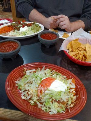 Burrito and enchilada combo on the bottom fajitas on the top chips regular salsa hot salsa.