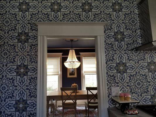 Italian tiled accent wall with elegant dining room chandelier