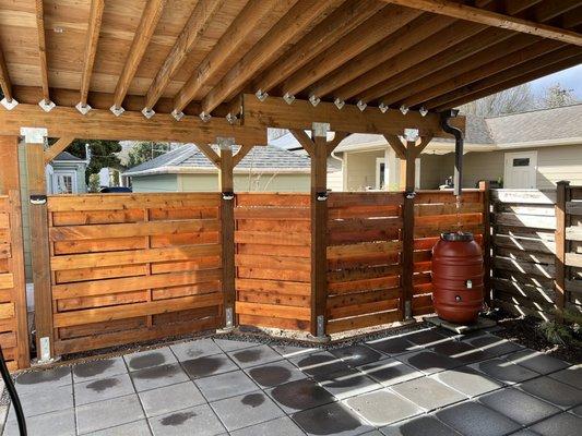 Carport with metal roof, pavers, rain barrel.