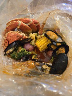 Seafood boil bag with black mussels and dungeness crab