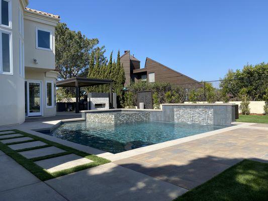 A new complete backyard with pool and spa, outdoor kitchen, BBQ island, fire place, fire pit, syn lawn, all designed by Landscape Logic