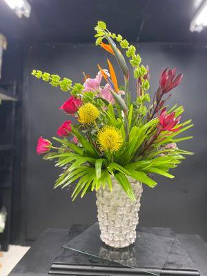 yellow pincushion protea, birds of paradise, pink oriental lily, fuchsia roses, tropical palms, belles of Ireland, sunset protea