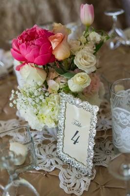 Crystal bling table number frame with elegant/minimalist black script alongside a lace wrapped vase.