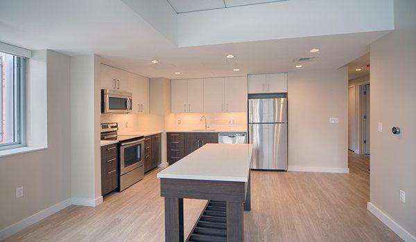 Brand-new kitchens feature two-tone modern cabinets, quartz countertops and an island